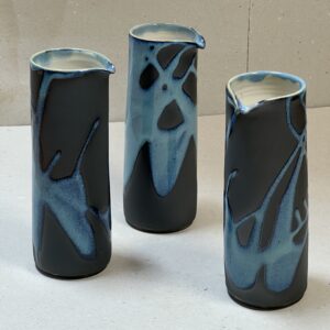 Henkelloser Krug schwarz mit hellblauem Muster